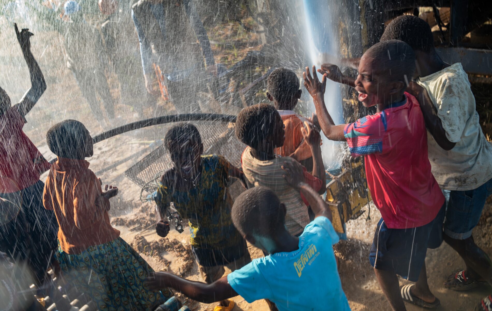Children celebrate as a geyser of water bursts forth from a newly dug borehole.